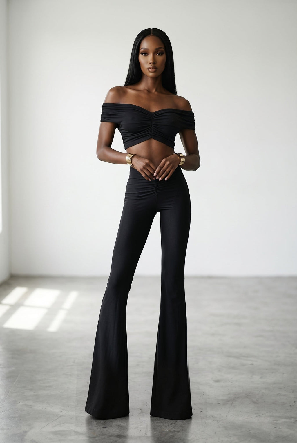 The Saint 54 black off-shoulder crop top and wide leg pants set with ruched detailing on a model.