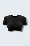 The Saint 54 black fitted crop top with a central fabric flower detail and vertical gathering at the front.