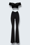 The Saint 54 black two-piece set with off-shoulder draped crop top and high-waisted wide-leg trousers.