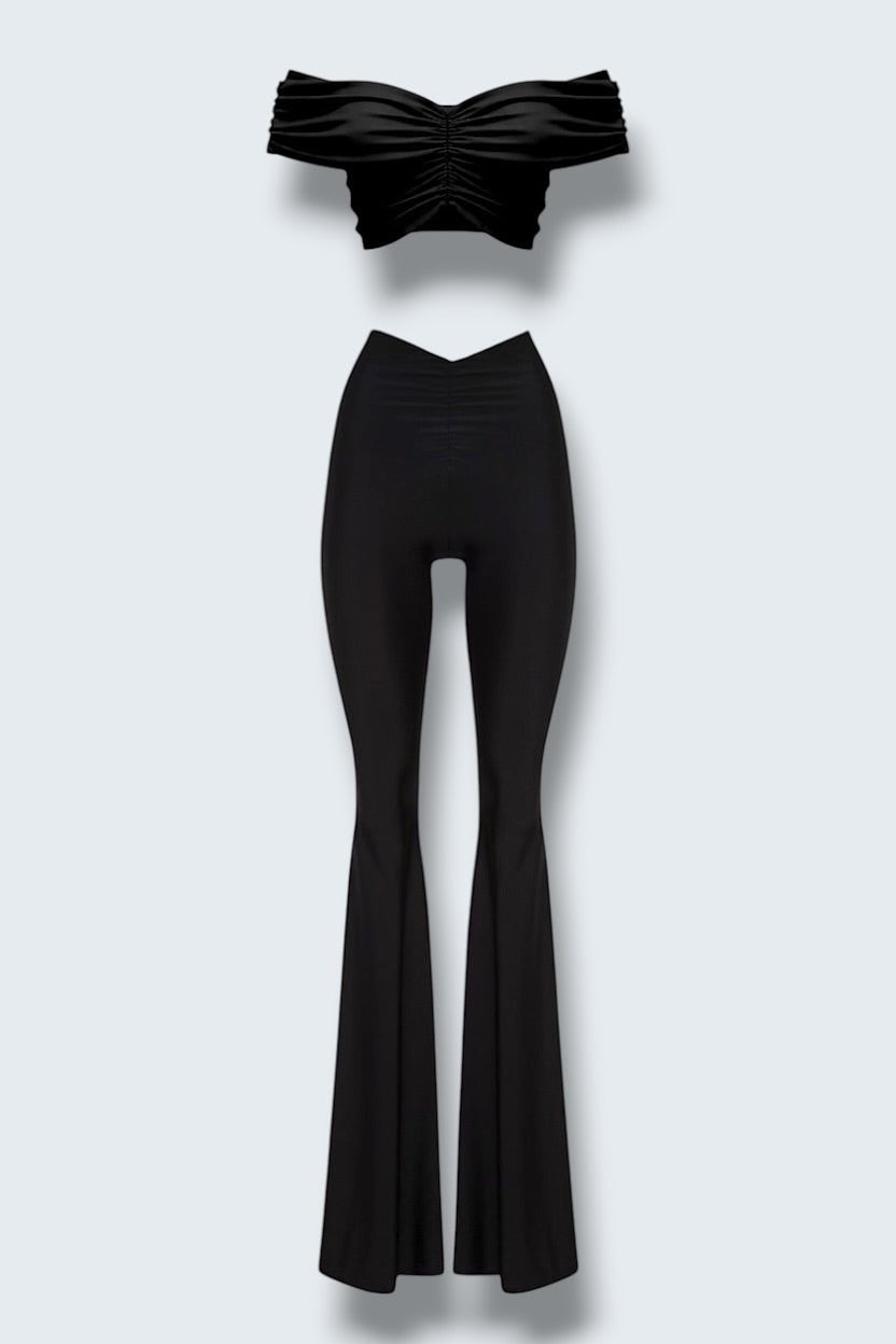 The Saint 54 black two-piece set with off-shoulder draped crop top and high-waisted wide-leg trousers.