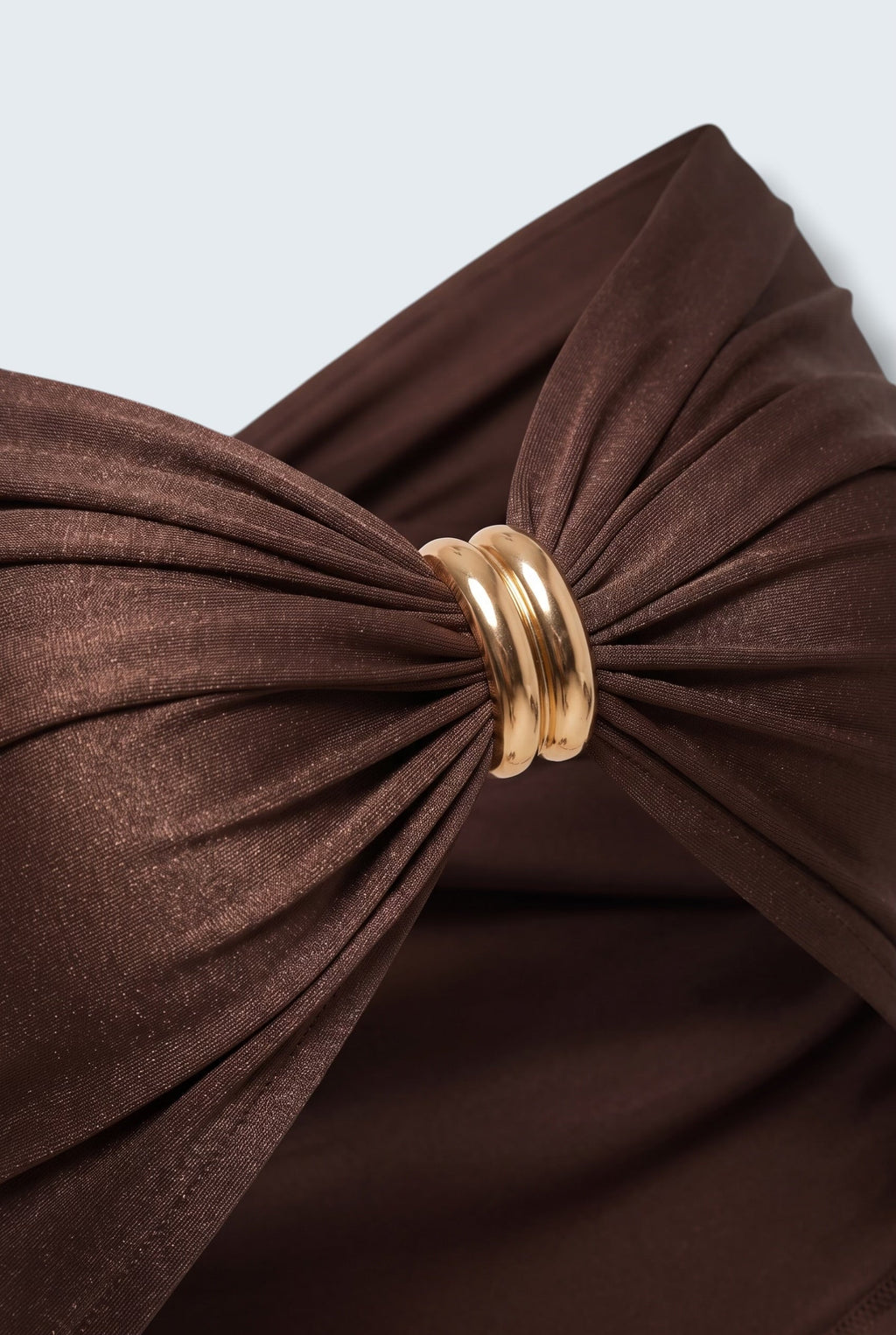 The Saint 54 Bad Girl top in dark chocolate stretch fabric with a central gold ring detail and elegant draping.