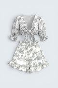 The Saint 54 grey toile print two-piece set with tie-front puff sleeve top and ruffled high-waisted mini shorts.