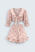 The Saint 54 pink floral two-piece set with tie-front puff sleeve crop top and high-waisted ruffled mini shorts.