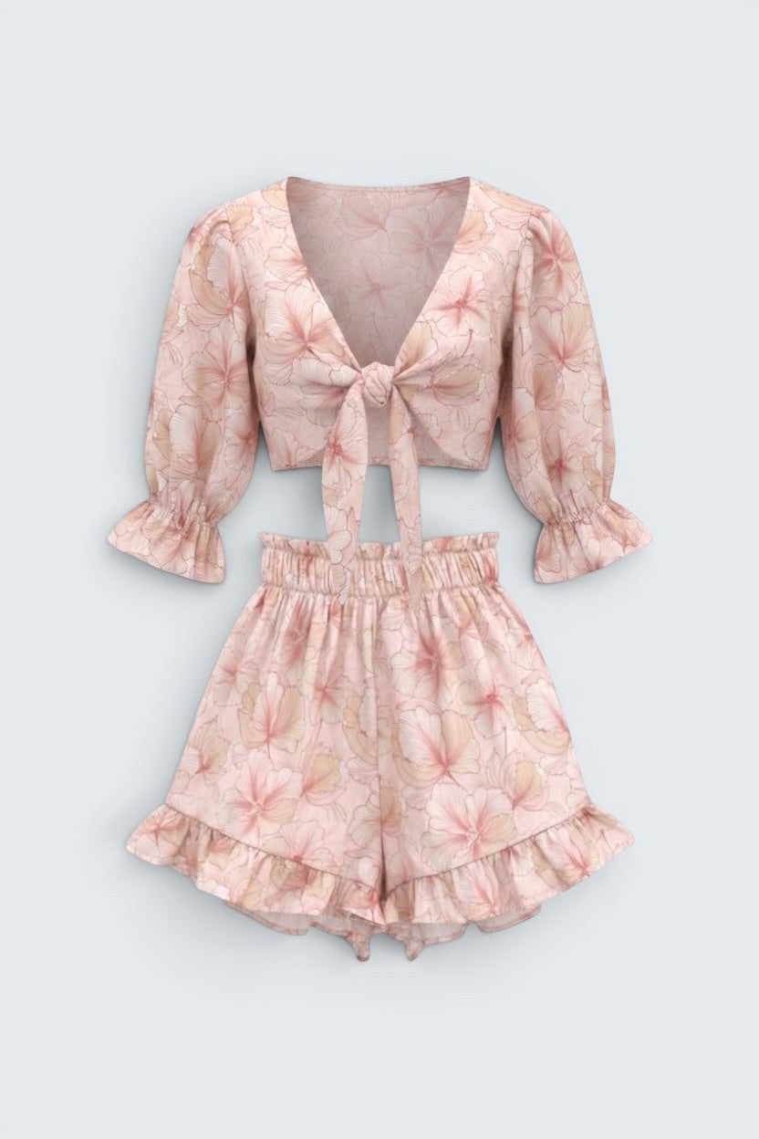 The Saint 54 pink floral two-piece set with tie-front puff sleeve crop top and high-waisted ruffled mini shorts.