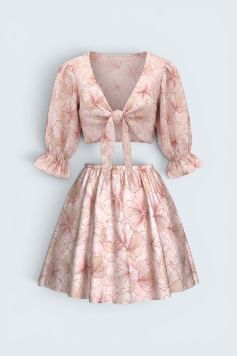 The Saint 54 pink floral two-piece set with a tie-front puff sleeve crop top and a high-waisted flared mini skirt.