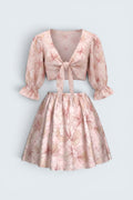 The Saint 54 pink floral two-piece set with a tie-front puff sleeve crop top and a high-waisted flared mini skirt.